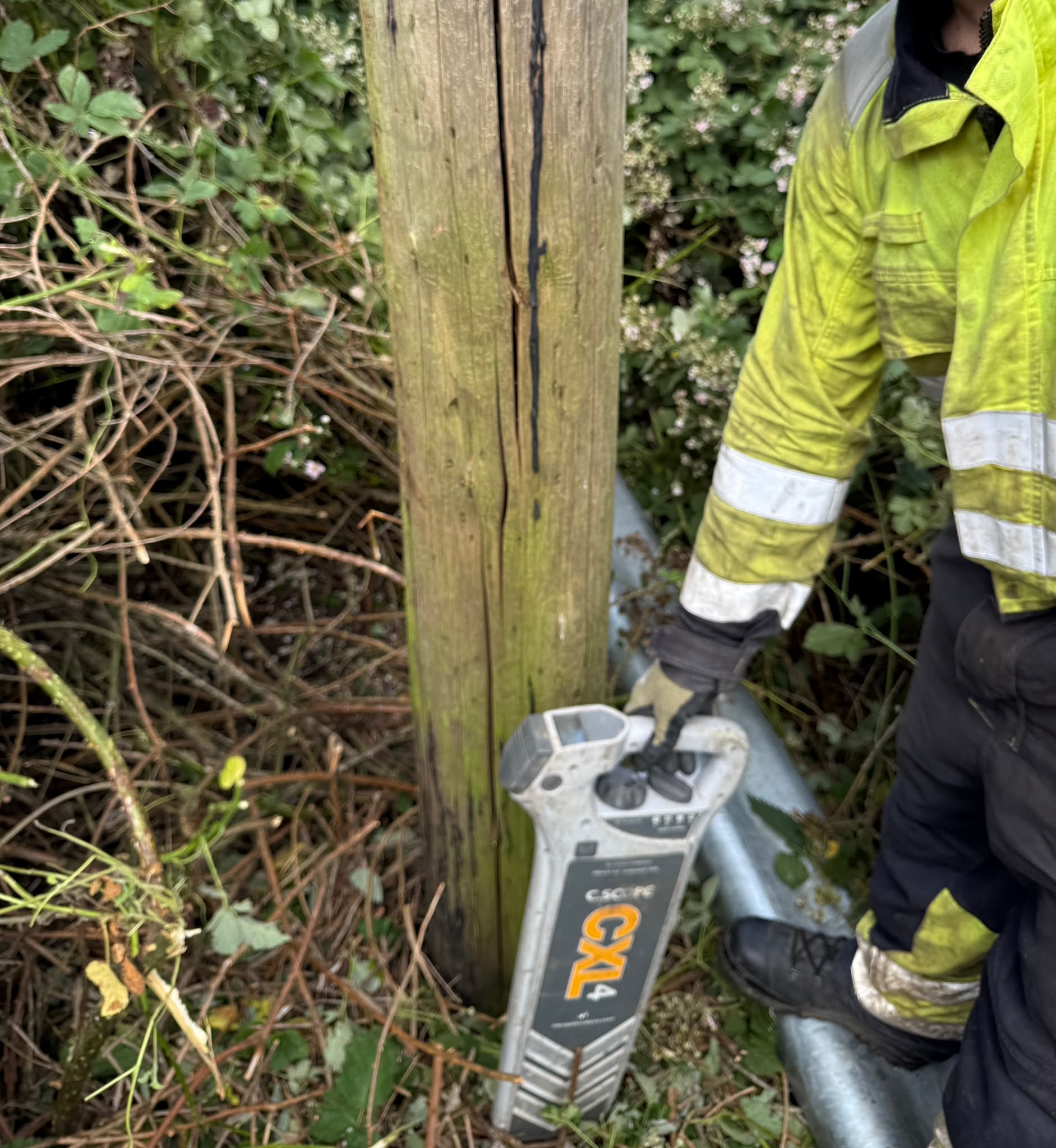 Cable locator being used to check for buried services at the base of a pole